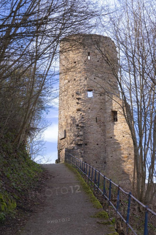 Steep path with blue railings from the castle hotel up to the ruins of Volmarstein Castle, remains of a tower on the right, branches and green vegetation on the slope to the left, Volmarstein, Ruhgebiet, Germany, Europe