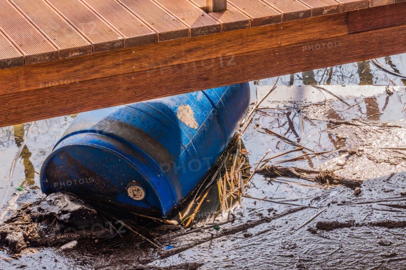 A raised deck beside a creek with a blue barrel partially hidden underneath, in South Korea