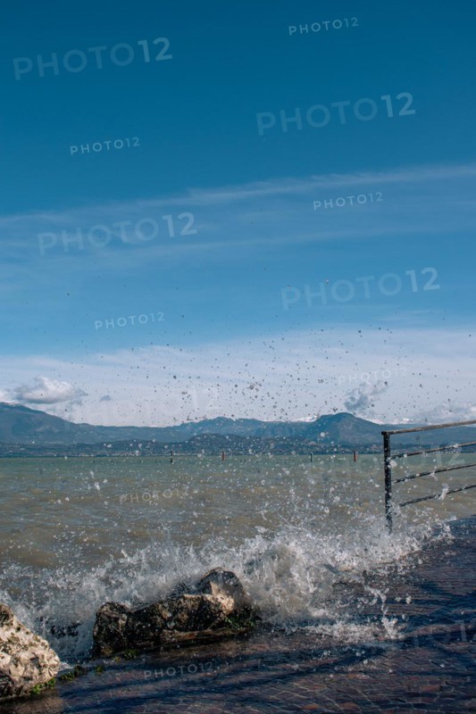 Splashing waves hitting rocks on the shore of Lake Garda, Sirmione, Lake Garda, Italy, Europe