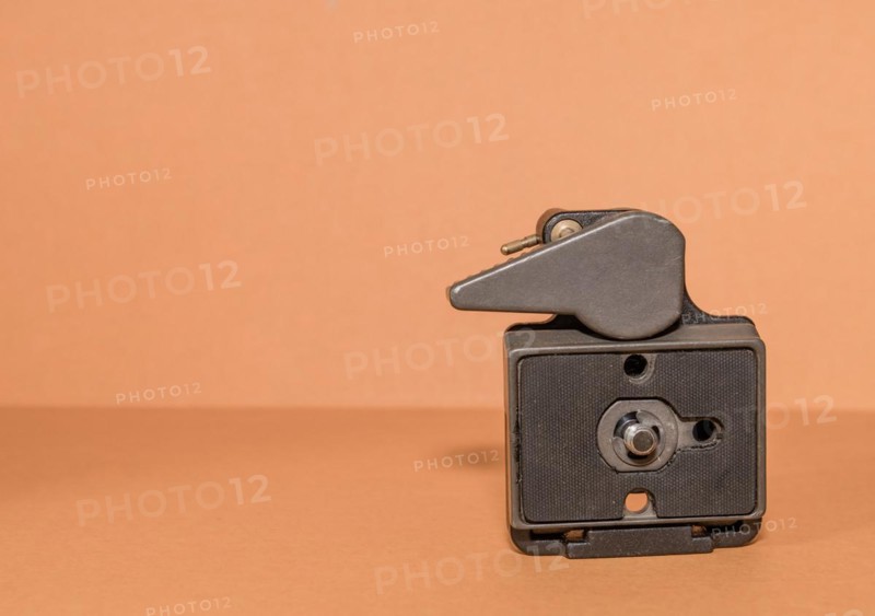 Closeup top view of quick release tripod head on brown background