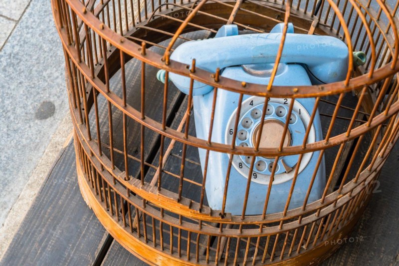 Old style rotary phone sitting in birdcage sitting outside on wooden step in Seoul, South Korea, Asia