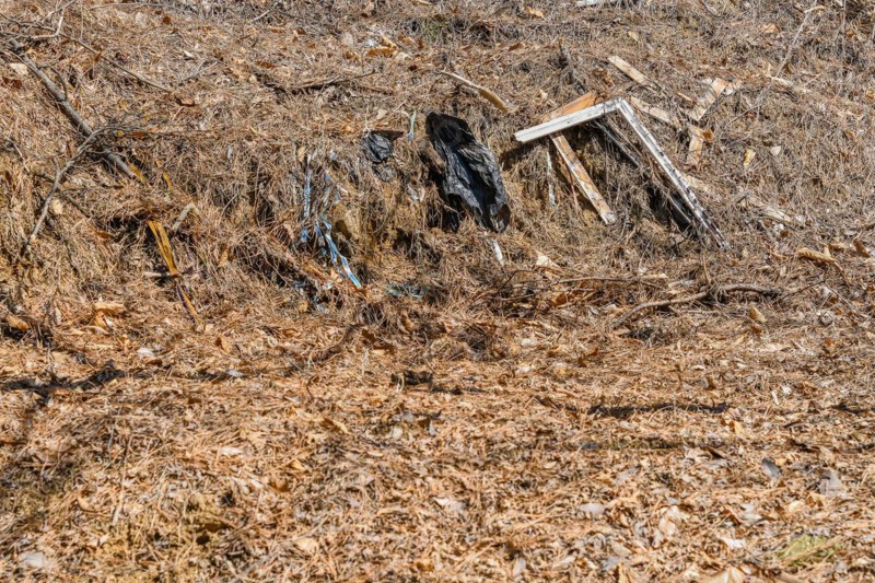 Discarded trash and black plastic bags pollute a dry grassy area, in South Korea