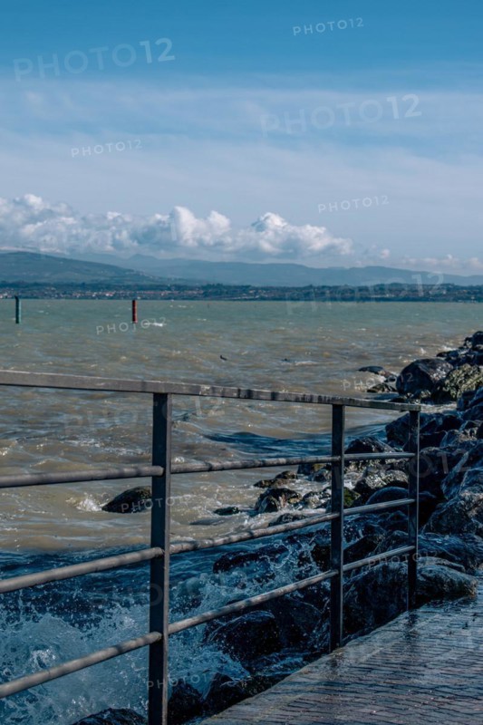 Splashing waves hitting rocks on the shore of Lake Garda, Sirmione, Lake Garda, Italy, Europe