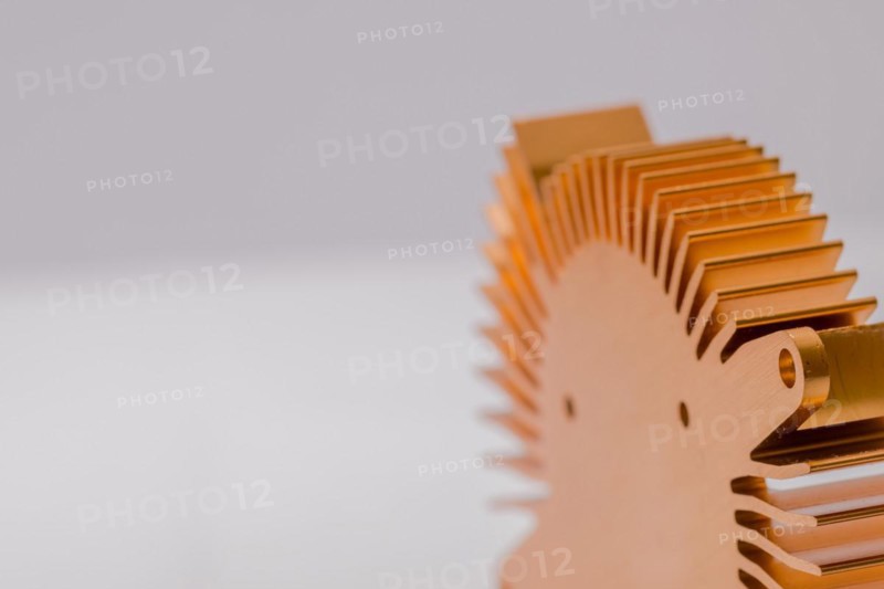 Closeup of fins and mounting flange on round copper computer heat sink on white background