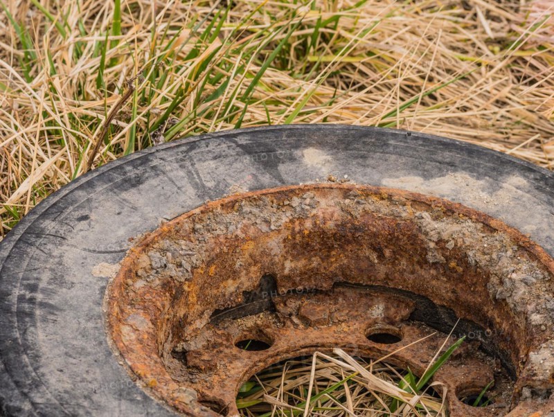 Close-up of a rusty tire rim surrounded by dry grass, in South Korea