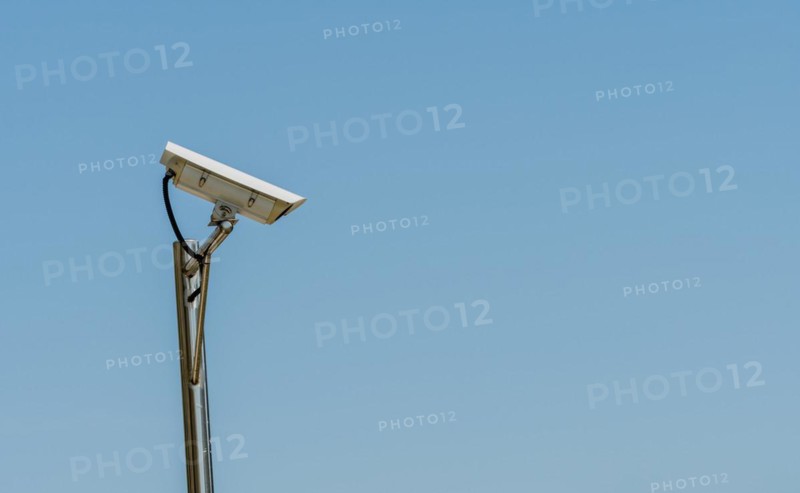 CCTV camera on shinny chrome plated pole against clear blue sky in South Korea