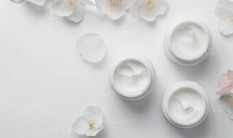 Three creme jar blank mockups nestled amidst delicate flower petals on a white background AI generated