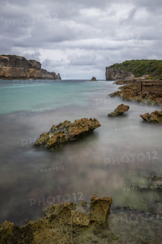 Rocky coast, long bay by the sea at sunset. Dangerous view of the Caribbean Sea. Tropical climate on a cloudy day in La Porte d'Enfer, Grande Terre, Guadeloupe, French Antilles, North America