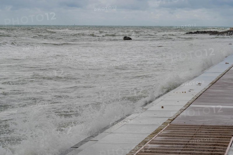 Waves crash against a sea wall creating whitecaps under an overcast sky, in Ulsan, South Korea, Asia