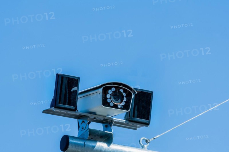 Closeup of closed circuit camera mounted on metal pole against light blue sky in background in South Korea