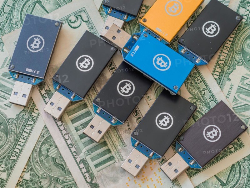 Multiple cryptocurrency USB hardware wallets spread over US dollar bills, in South Korea