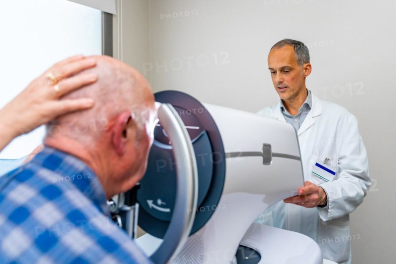 Rear view of a senior receiving a laser treatment for glaucoma in the eye in a clinic