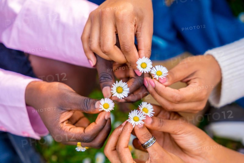 Top view of three unrecognizable african young female friends holding flowers and putting together in circle