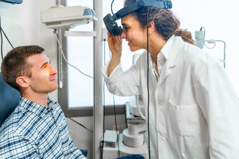 Female ophthalmologist checking the retina of a patient using the light of a retinoscope