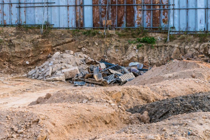 Construction site with debris, scaffolding, and piles of dirt under a blue sky, in South Korea