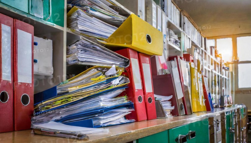 An office cupboard full of disorganised folders and piles of paper reflects the challenge of filing, symbol bureaucracy, AI generated, AI generated