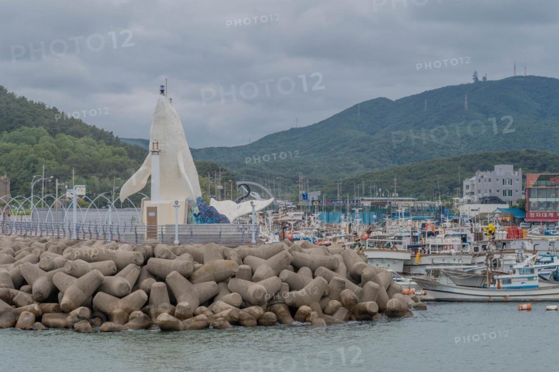 Harbor view with a white lighthouse, docked boats, and tetrapod breakwater, in Ulsan, South Korea, Asia