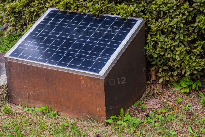 Closeup of small solar panel in front of green shrubbery in South Korea