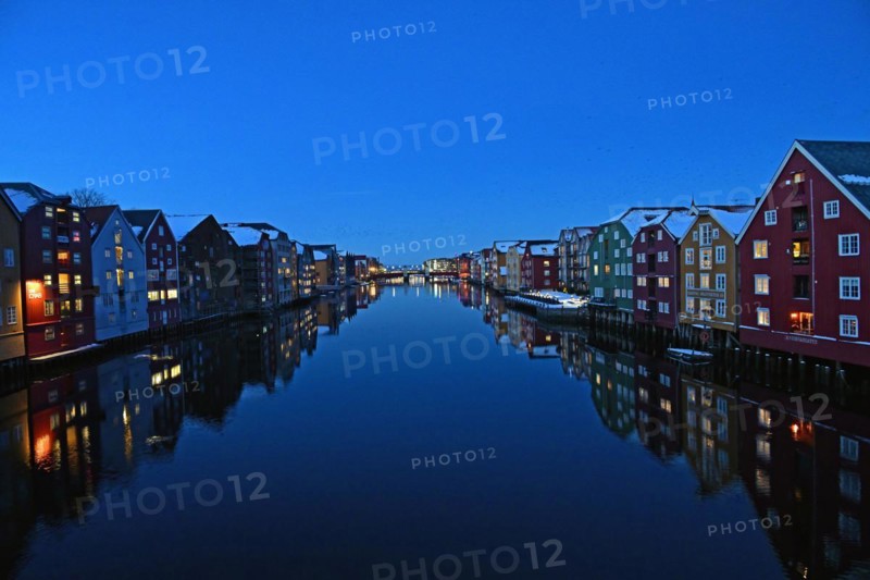 Historic warehouse buildings reflected in the river Nidelva at dusk, Bryggene, Trondheim, Norway, Europe