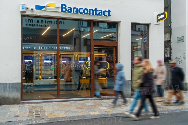 Shoppers walking past indoor ATM cash dispenser of bank neutral Bancontact CASH point in shopping street at city Ghent, Gent, East Flanders, Belgium, Europe