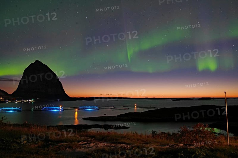 Northern lights (aurora borealis) mingle with sunset, sea, striking mountains and fish farm, Lovunden, Helgeland coast, Traena, Norway, Europe