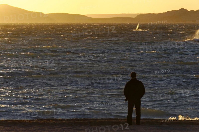 Marseille in the evening, A person stands on the shore and looks at the sea during sunset, Marseille, Departement Bouches-du-Rhone, Region Provence-Alpes-Cote d'Azur, France, Europe