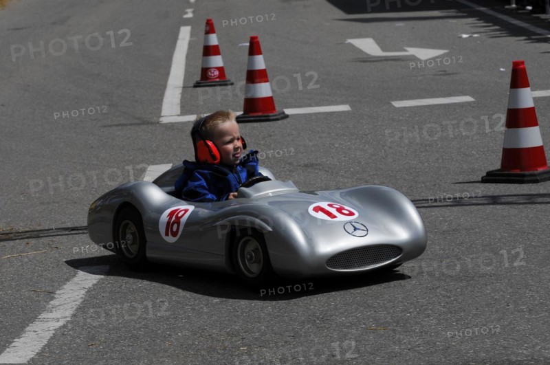 Smiling child enjoying a ride in a silver soapbox on a closed-off road, SOLITUDE REVIVAL 2011, Stuttgart, Baden-Wuerttemberg, Germany, Europe