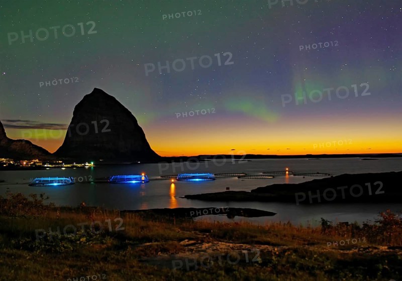 Northern lights (aurora borealis) mingle with sunset, sea, striking mountains and fish farm, Lovunden, Helgeland coast, Traena, Norway, Europe