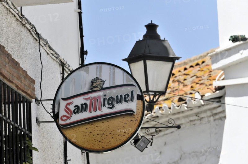Solabrena, A round beer advertising sign for San Miguel on a wall next to a lantern, Andalusia, Spain, Europe