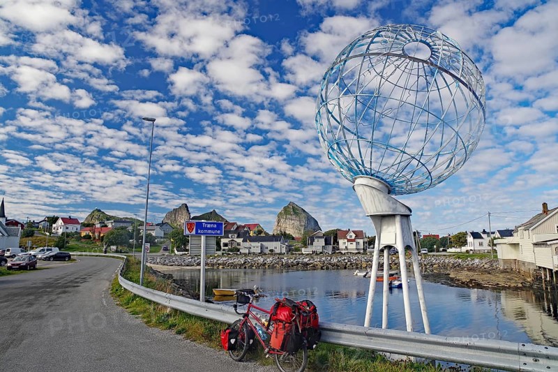 Packed touring bike in front of a huge globe and a harbour, Traena, Lovunden, Helgeland coast, Norway, Europe