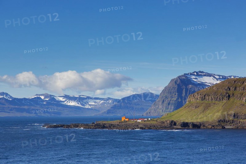Rugged mountains and orange lighthouse at Skalanes along the fjord Seyoisfjoerour, Seydisfjoerdur in summer, Eastern Region, Austurland, Iceland, Europe