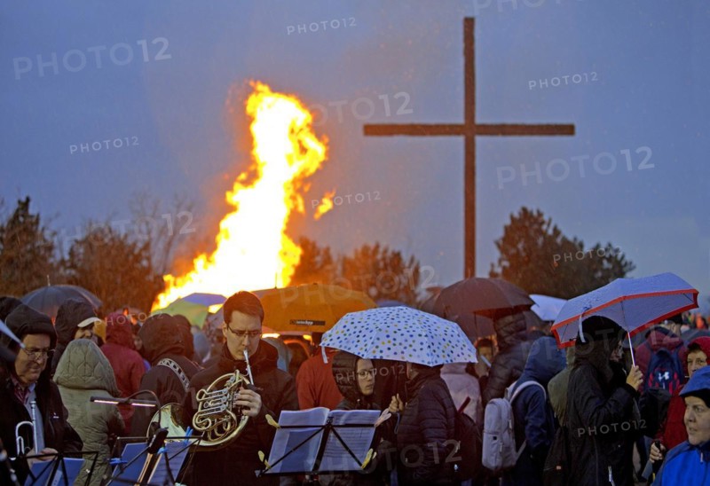 Musicians with a double horn in front of the Easter bonfire on the Haniel spoil tip with the summit cross in the rain, Bottrop, Ruhr area, Germany, Europe