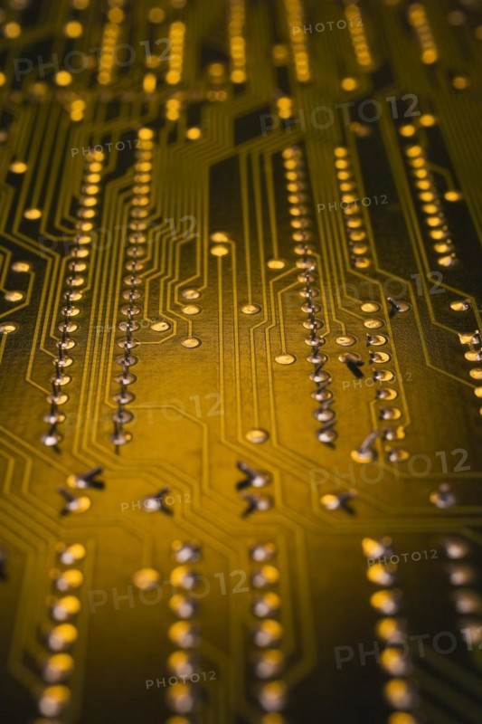 Close-up of golden yellow lighted electronic computer circuit board with lines and silver solder points, Studio Composition, Quebec, Canada, North America
