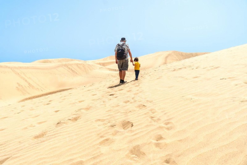 Father and son on vacation laughing running in the dunes of Maspalomas, Gran Canaria, Canary Islands