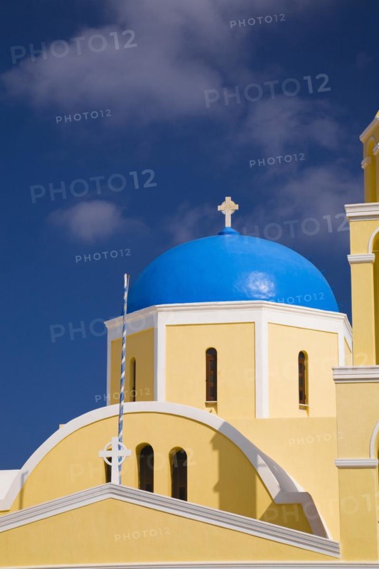 Close-up of yellow painted roughcast cladded chapel with cross on blue dome, Oia village, Santorini, Greece, Europe