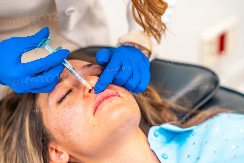 Close-up of a caucasian adult woman getting a Botox injection in the lips in a beautician professional clinic