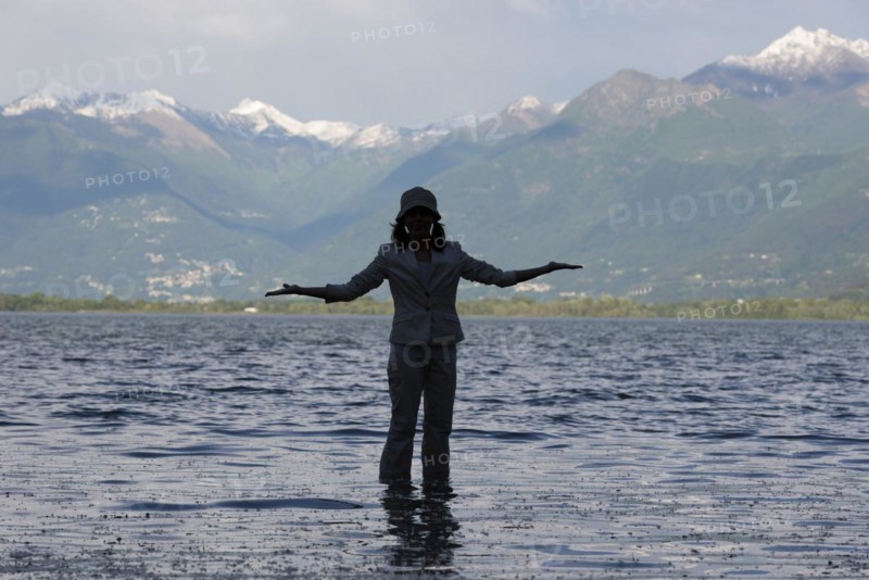 Woman Standing in a Flooding Alpine Lake Maggiore with Snowcapped Mountain in Locarno, ticino, Switzerland. | MR:yes Maria-CH-20-04-2022
