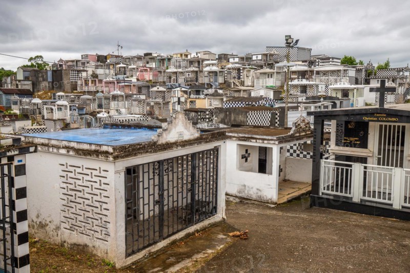Famous cemetery, many mausoleums or large tombs decorated with tiles, often in black and white. Densely built buildings under a dramatic cloud cover Cimetiere de Morne-a-l'eau, Grand Terre, Guadeloupe, Caribbean, North America