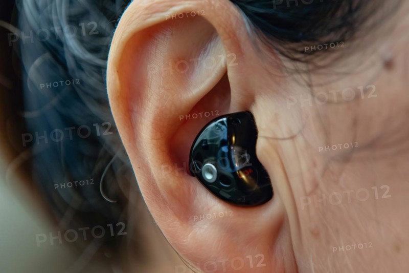 Small black hearing aid in person's ear. KI generiert, generiert, AI generated