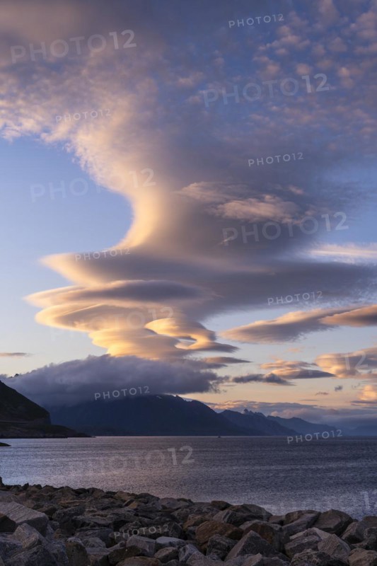 Cloudscape, view from Hamnoy over the sea along Moskenesoya, Flakstadoya and Vestvagoya. Several lenticular clouds (lenticularis) in the blue sky. At night at the time of the midnight sun in good weather. Early summer. Lofoten, Norway, Europe
