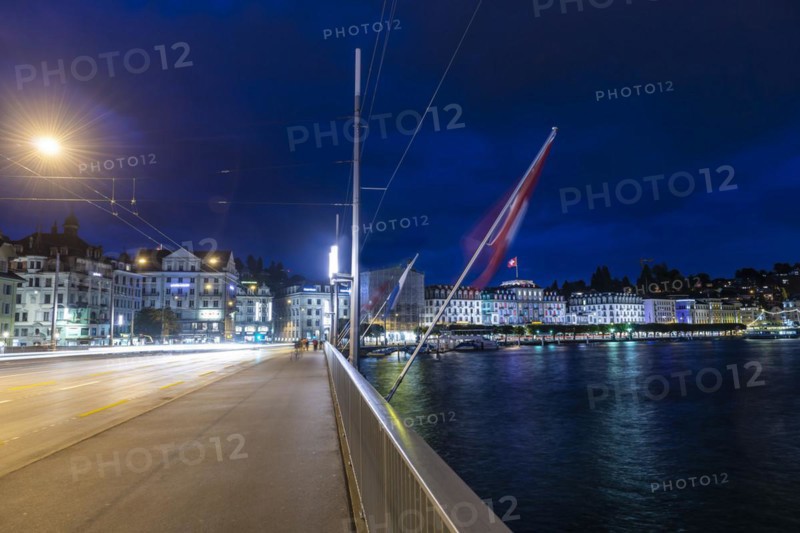 Cityscape and a Bridge with Swiss Flag and Lake Lucerne in Long Exposure at Night in Switzerland