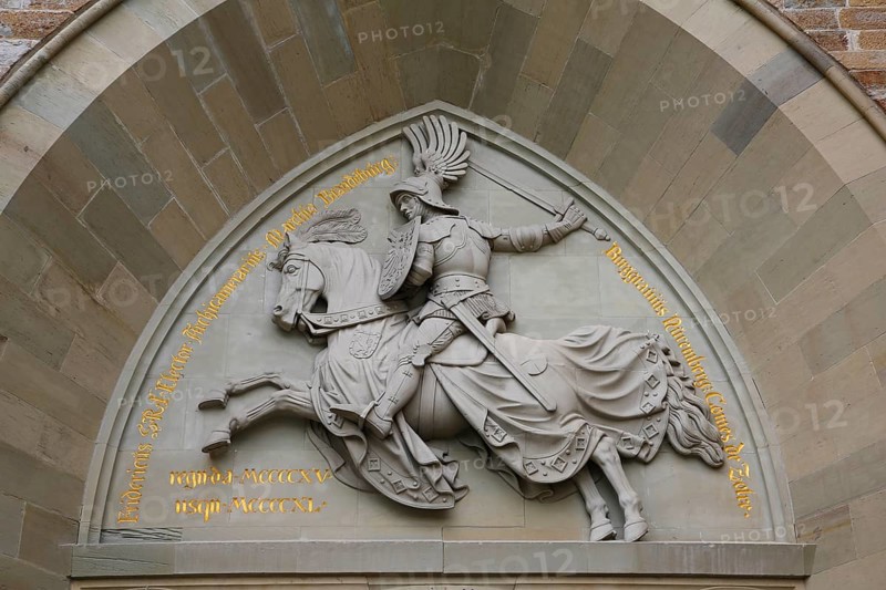 Eagle Gate, stone relief on the outer castle gate, knight figure on horse, armour, inscription, Hohenzollern Castle, ancestral castle of the Prussian royal and German imperial dynasty of Hohenzollern, summit castle, historic building by the Berlin architect Friedrich August Stueler, architecture, neo-Gothic, castle building, aristocratic residence, Bisingen, Zollernalbkreis, Baden-Wuerttemberg, Germany, Europe