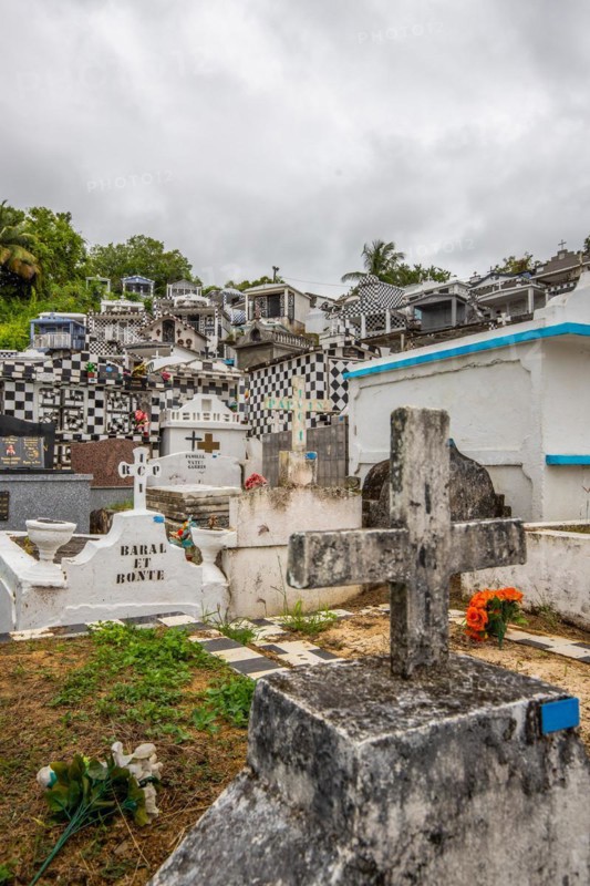Famous cemetery, many mausoleums or large tombs decorated with tiles, often in black and white. Densely built buildings under a dramatic cloud cover Cimetiere de Morne-a-l'eau, Grand Terre, Guadeloupe, Caribbean, North America