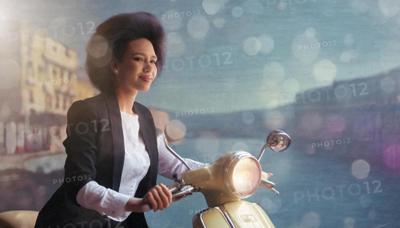 Elegant woman on a vintage scooter with pastel tones and soft bokeh lights, blurry moody landscaped background with bokeh effect, AI generated