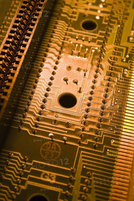 Close-up of golden orange and yellow lighted electronic computer circuit board with silver solder points and lines, Studio Composition, Quebec, Canada, North America