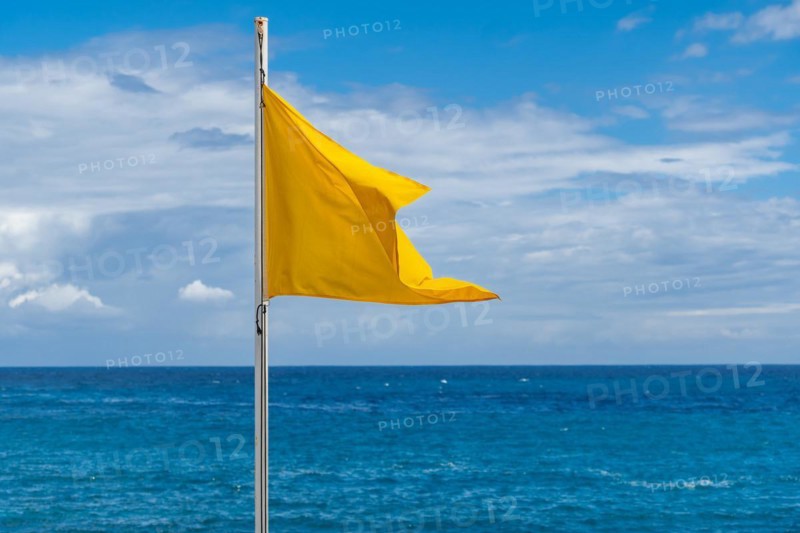 Yellow flag on the beach in summer summer, lifeguards sign