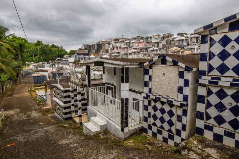 Famous cemetery, many mausoleums or large tombs decorated with tiles, often in black and white. Densely built buildings under a dramatic cloud cover Cimetiere de Morne-a-l'eau, Grand Terre, Guadeloupe, Caribbean, North America