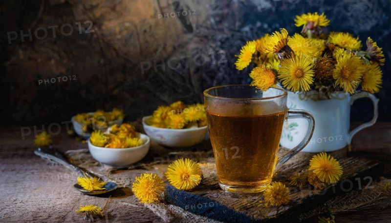 Cosy tea set-up with coltsfoot and fresh flowers arranged on a wooden table, coltsfoot tea, medicinal plant coltsfoot, Tussilago farfara, KI generiert, AI generated