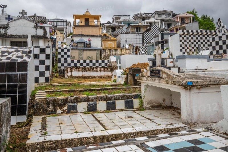 Famous cemetery, many mausoleums or large tombs decorated with tiles, often in black and white. Densely built buildings under a dramatic cloud cover Cimetiere de Morne-a-l'eau, Grand Terre, Guadeloupe, Caribbean, North America