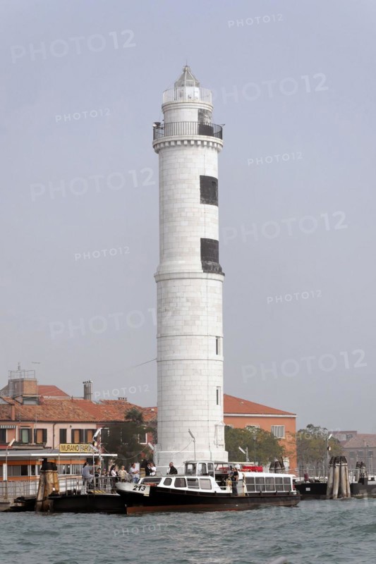 Island of Murano, A white lighthouse stands on the water with a small boat nearby, Venice, Veneto, Italy, Europe